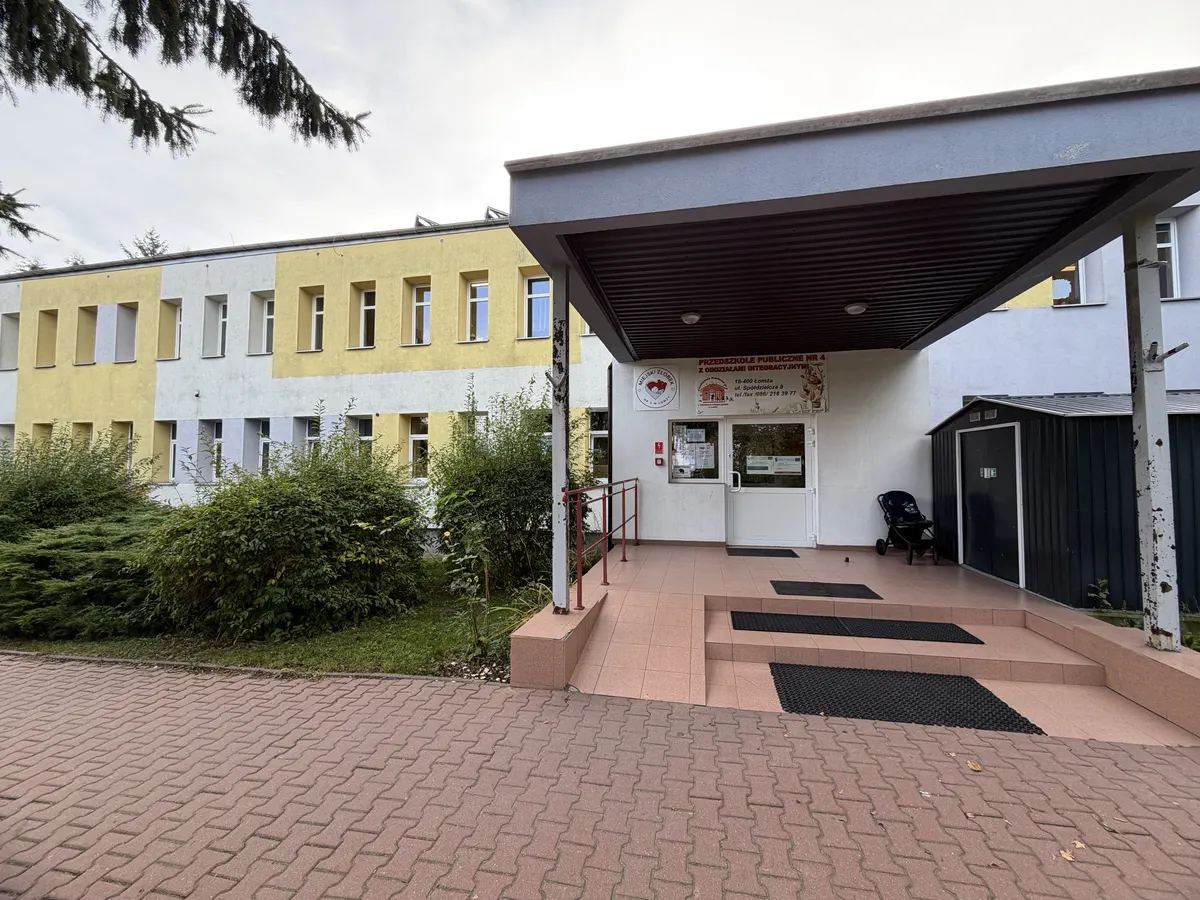 Wejście główne do przedszkola: zadaszony podjazd z pochylnią i poręczą, obok schody.